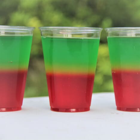 Three Jello cups in a row, with a red base layer and a green top layer.