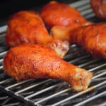 Glazed chicken drumsticks on a smoking rack.