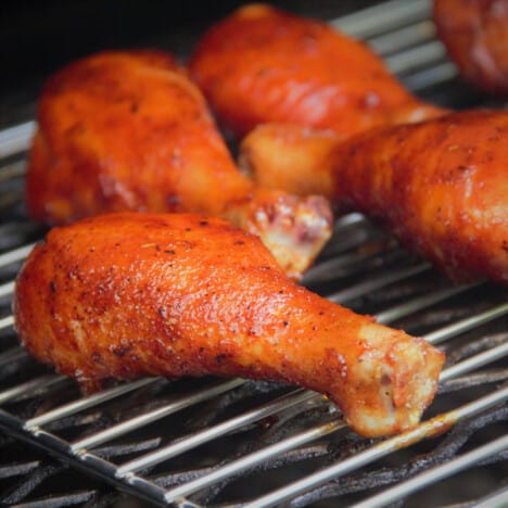 Glazed chicken drumsticks on a smoking rack.