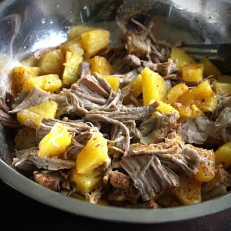 Stainless bowl filled with pulled pork and pineapple pieces.