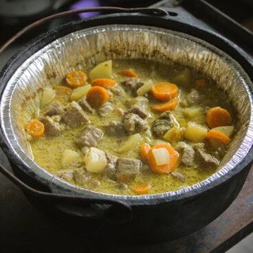 A cooked yellow curry sitting in a liver Dutch oven.