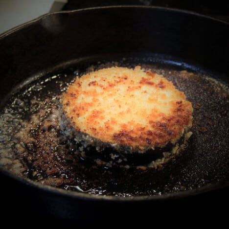 A single eggplant parma with browned breadcrumbs in a skillet.