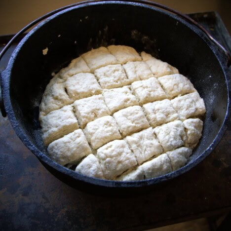 A Dutch oven with a raw dough that is marked in a gride shape.