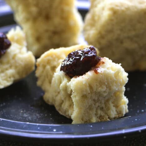 A ginger beer scone topped with butter and jam served on a blue camp plate.