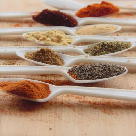 Looking across a range of spoons with a variety of spices in them.