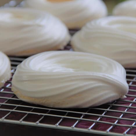 A row of pavlovas cooling on a wire rack.
