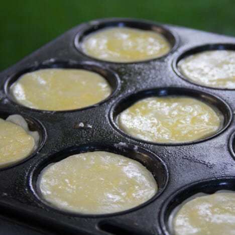 A muffin tin filled with meat pies and topped with unbaked puff pastry.