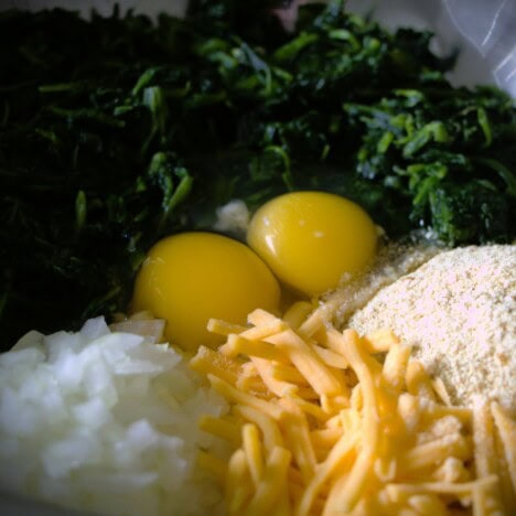 Spinach, breadcrumbs, shredded cheese, diced onion, and the eggs sitting together in a bowl.