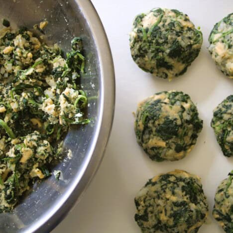 A bowl of the spinach mix next to shaped spinach patties.