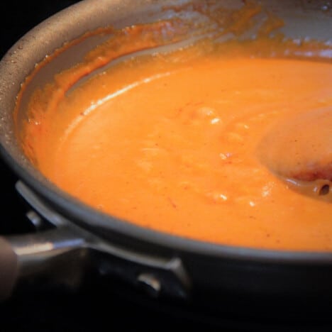 A red sauce cooks in a skillet.