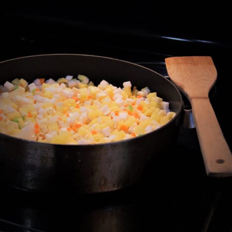 A cast iron skillet filled with chopped vegetables on a stove top.