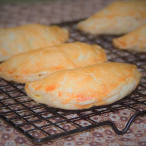 Golden brown pasties cooling on a wire rack.