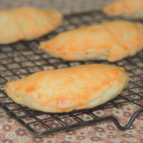 Golden brown vegetable pasties cooling on a wire rack.