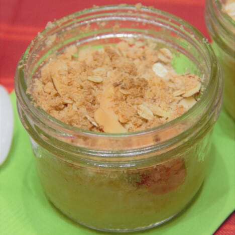 A close up of an apple crisp in a small glass canning jar.