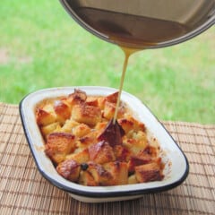 The Bourbon Sauce is being poured over the Bread and Butter Pudding while still in a casserole dish.