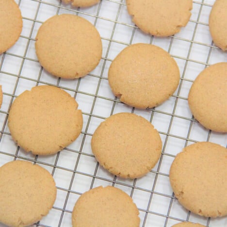 Rows of baked gingersnap cookies on a cooling rack.