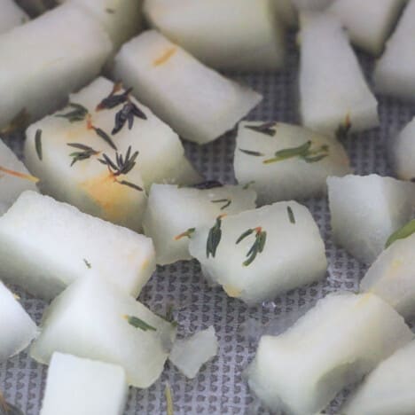 Close-up of cubed apple pieces topped with thyme leaves.