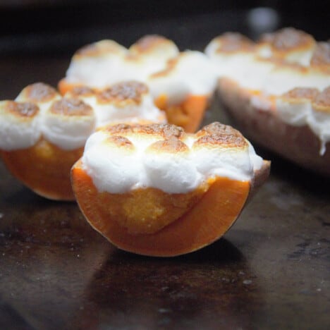 A stuffed sweet potato is cut in half, showing the filling and toasted marshmallows.