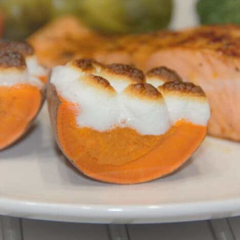 A stuffed sweet potato is cut in half, showing the filling and toasted marshmallow topping.