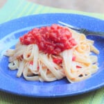A serving of noodles topped with tomato sauce on a blue camping plate.