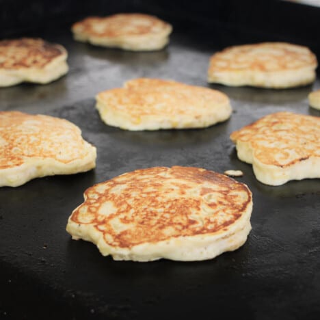 Corn fritters cooked to a golden brown on a flat top grill.