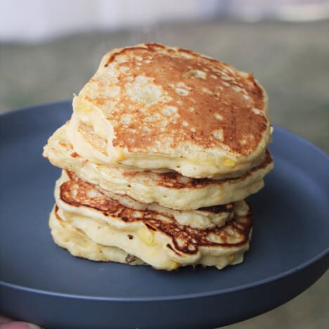 A stack of cooked corn fritters on a grey camp plate.