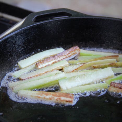 Sticks of cucumber sautéing in a skillet.