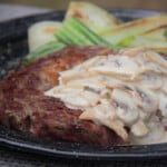 Close up of a seared steak topped with a creamy mushroom sauce.