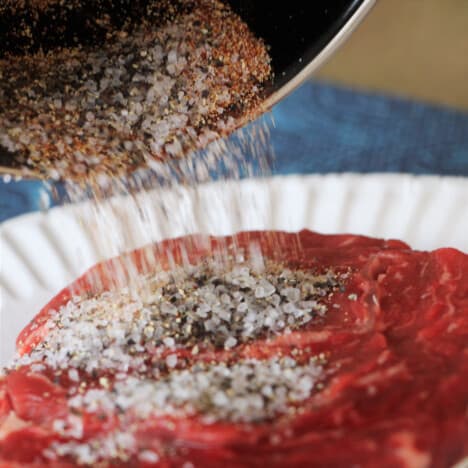 A basic rub being gently tipped onto a steak.