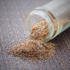 A bottle of rub is decoratively spilling onto a dark colored placemat.