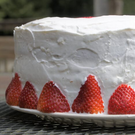 Close up of the rustic topping finish on the sides of the cake and fresh strawberries decorating the base.