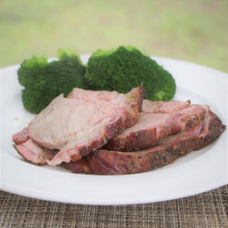 Plate with slices of smoked lamb and broccoli on it.