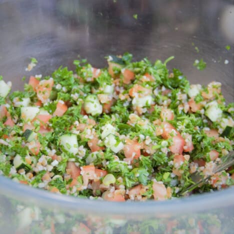 Looking into a large glass bowl filled with tabbouleh salad.