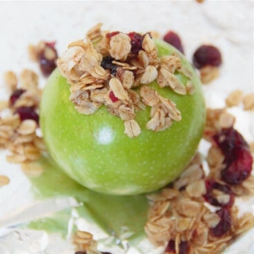 A raw green apple stuffed with oats and dried raisins, sitting on a piece of foil.