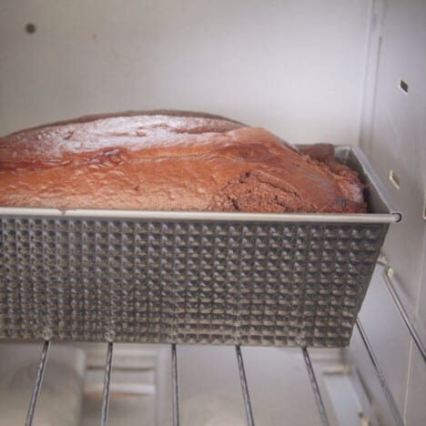 Close up of a chocolate cake in a cake tin baking in a camp oven.