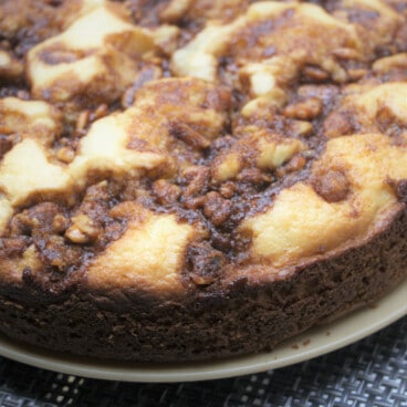 A cooked coffee cake with a brown walnut textured topping served on a plate.