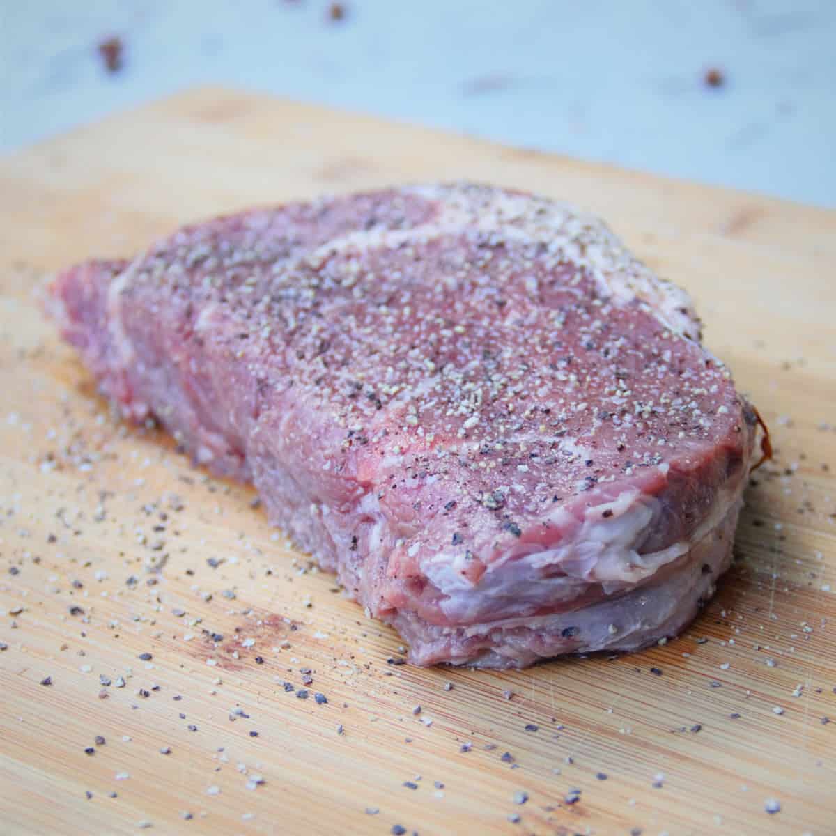 The ribeye steak is seasoned with the homemade three pepper rub waiting to be cooked.
