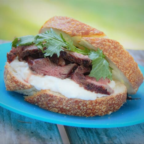 A close up image of a ribeye sandwich focused on the sliced ribeye.