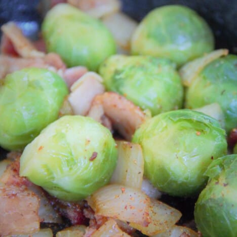Close up of raw Brussels sprouts and seasoned chopped onions.