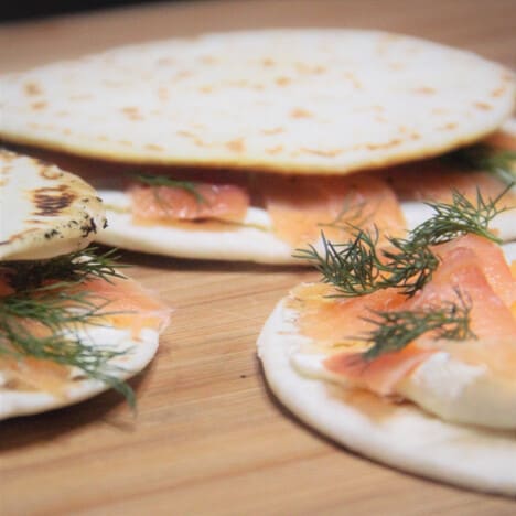Close up of three smoked salmon quesadillas on a wooden cutting board.