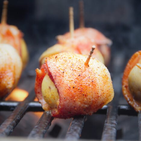 A close up of a cooked bacon-wrapped baby potato on the grill.