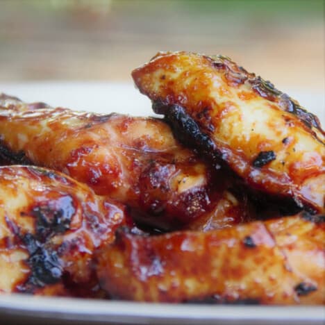 A close up shot of a pile of grilled and glazed chicken drumettes.