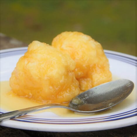 Two Golden Syrup Dumplings served on a plate ready to eat.