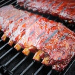 Two racks of glazed ribs sitting on a grill with grill marks on them.