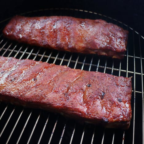 Two racks of rubbed ribs almost finished with the smoking stage in a smoker.