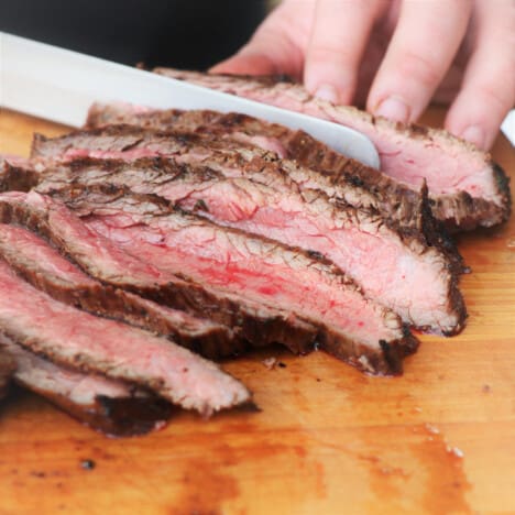 A medium-rare grilled flank steak being sliced.