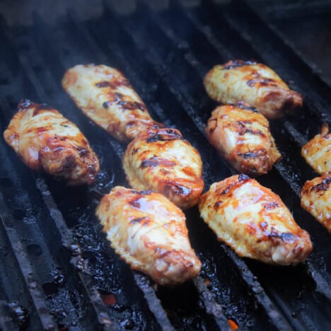 Chicken drumettes cooking on a grill.