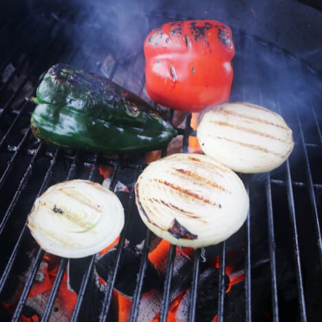 Charcoal grill cooking bell peppers and onions.
