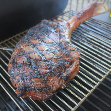 A cooked ribeye steak sitting in the cool zone of the BBQ.