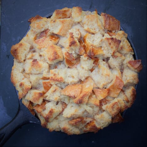 Aerial view of a banana bread pudding just removed from the camp oven still in the skillet with a golden brown top.